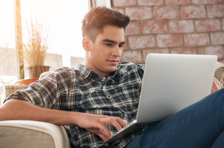 Businessman using laptop on sofa in coffee shopの写真素材