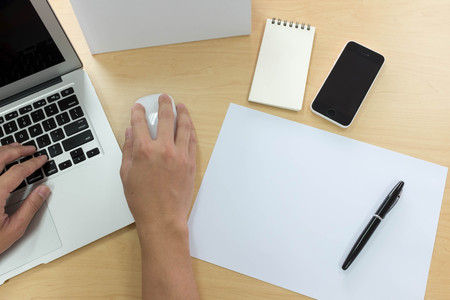 Hands of man using laptop with smart phone, tablet, pen, calendar and a piece of paperの写真素材