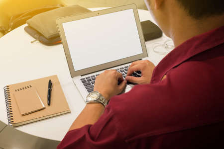 Man using laptop on table with note book and penの写真素材