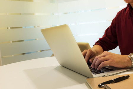 cropped shot of a young man working from home using laptop computer, man at his workplace using technologyの写真素材