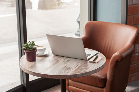 Laptop with tablet, pen and a cup of fresh coffee latte art on wooden table in coffee shopの写真素材
