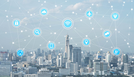 Businessman standing on roof top of skyscrapper looking at icons with cityscape in background, internet of things conceptualの写真素材