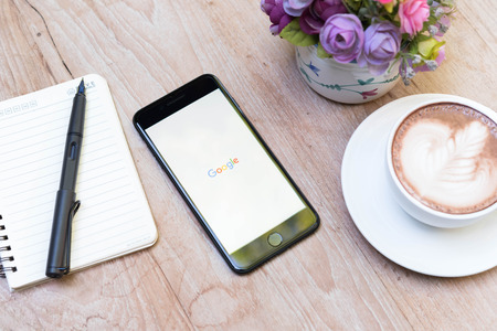CHIANG MAI, THAILAND - NOVEMBER 14th, 2016: Iphone7 Plus jet black serie with icons of Google on screen with latte art on wooden table, new generation of smartphone, age of smartphone, smartphone in everyday lifeのeditorial素材