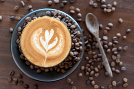 Top view of fresh coffe, latte art with coffee bean on wooden tableの写真素材
