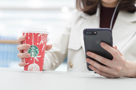 Bangkok ,Thailand December 12 : woman hold starbucks hot beverage cup in Christmas theme using smartphone, Iphone7のeditorial素材