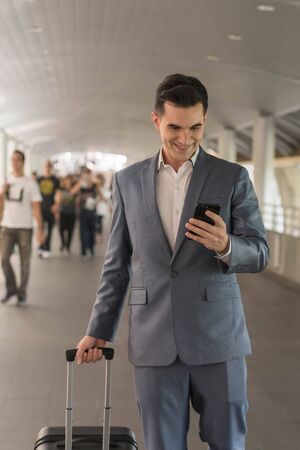 Westerner Business man talking via smart phone on the walk way with people in backgroundの写真素材