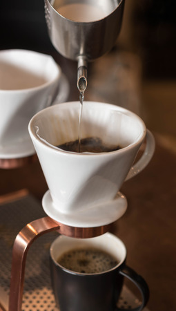 Hand of barista dripping coffee with white dripper filered by paperの写真素材