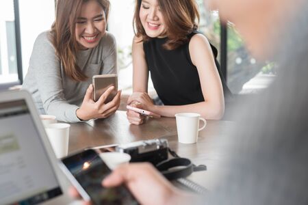 Group of friends meeting in a coffee shop chatting to each other while using smartphone tablet and laptop, internet of things conceptualの写真素材