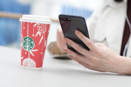 Bangkok ,Thailand December 12 : woman using Iphone7 plus hold starbucks hot beverage cup in Christmas themeのeditorial素材