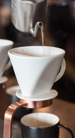 Hand of barista dripping coffee with white dripper filered by paperの写真素材