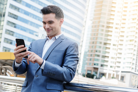 Westerner Business man talking via smart phone with skyscraper in backgroundの写真素材