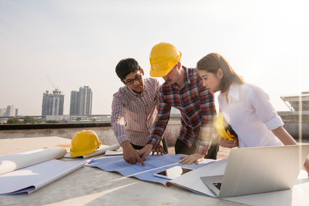 three construction engineers working outdoors in construction siteの写真素材