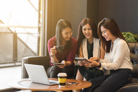 Group of friends happily hang out in a coffee shop chatting to each other while using smartphone tablet and laptop, internet of things conceptualの写真素材