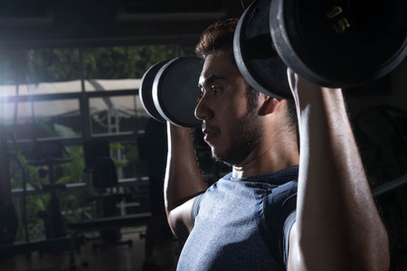 Man lift weight on shoulder press with studio light shotの写真素材