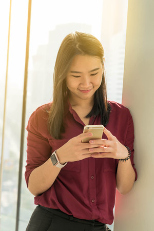 Girl use smartphone stand by the windowの写真素材