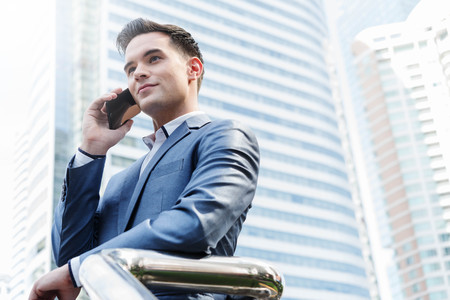 Westerner Business man talking via smart phone with skyscraper in backgroundの写真素材