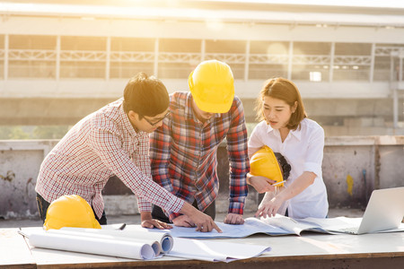 three construction engineers working outdoors in construction siteの写真素材