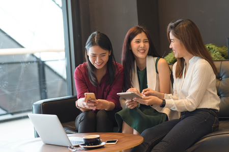 Group of friends happily hang out in a coffee shop chatting to each other while using smartphone tablet and laptop, internet of things conceptualの写真素材