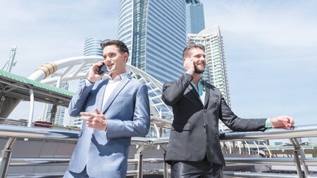 Two Westerner Business men talk and use smart phoneの写真素材