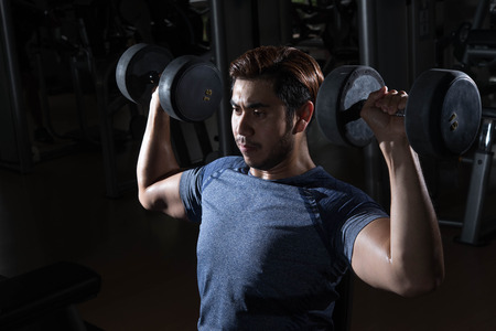 Man lift weight on shoulder press with studio light shotの写真素材