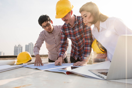 three construction engineers working outdoors in construction siteの写真素材