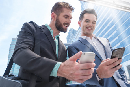 Two Westerner Business men talk and use smart phoneの写真素材