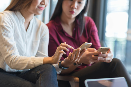 Group of friends meeting in a coffee shop chatting to each other while using smartphone tablet and laptop, internet of things conceptualの写真素材