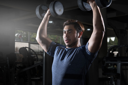 Man lift weight on shoulder press with studio light shotの写真素材