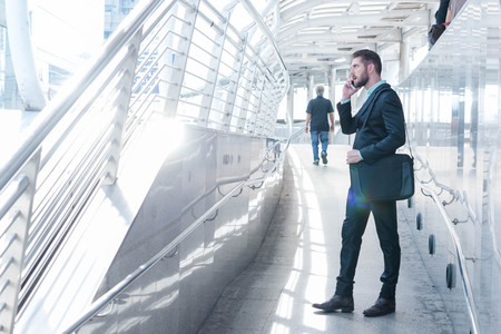 westerner business man talking via cellphone in public walk wayの写真素材