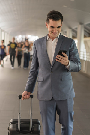 Westerner Business man talking via smart phone on the walk way with people in backgroundの写真素材