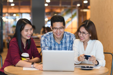 Group of friends meeting in a coffee shop chatting to each other while using smartphone tablet and laptop, internet of things conceptualの写真素材