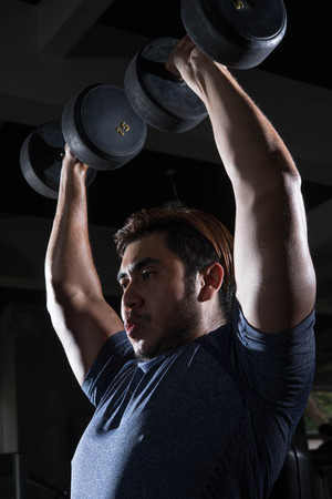 Man lift weight on shoulder press with studio light shotの写真素材