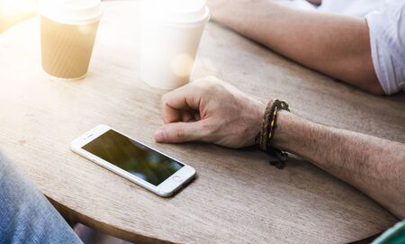 Hipster man using smartphone on wooden tableの写真素材