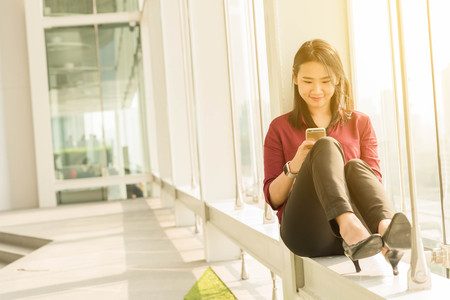 Girl use smartphone sit by the windowの写真素材
