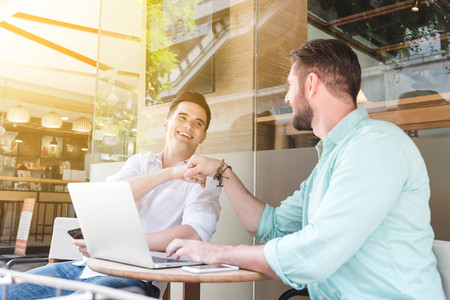 Two Westerner Business men talk and use smart phone and laptop make fist bumpの写真素材