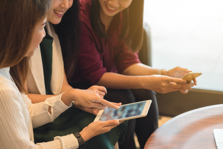 Group of friends meeting in a coffee shop chatting to each other while using smartphone tablet and laptop, internet of things conceptualの写真素材