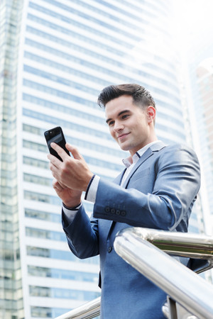 Westerner Business man talking via smart phone with skyscraper in backgroundの写真素材