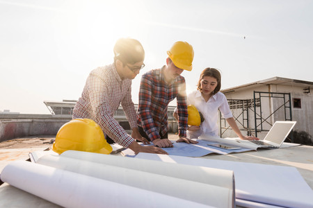 three construction engineers working outdoors in construction siteの写真素材