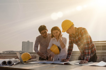 three construction engineers working outdoors in construction siteの写真素材