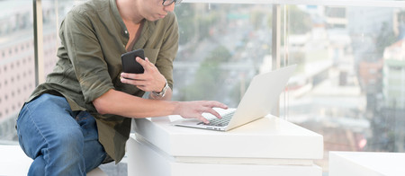 Young man use smartphone and laptop in afternoon, technology lifestyle of new generation of nomad...