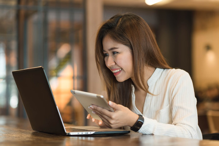 Woman use tablet and laptop in coffee shopの写真素材