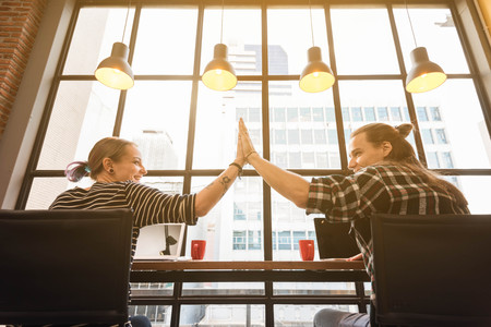 Two freelance give five to each other during work in cafe, freelance conceptual