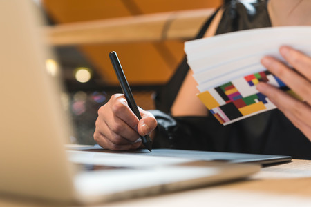 Close up hands of beautiful asian woman designer in black dress working with mouse pen while look at color chartの写真素材