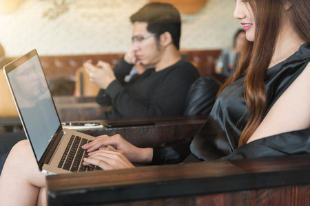 Beautiful asian woman in black dress working with laptop taking note in coffeeshopの写真素材