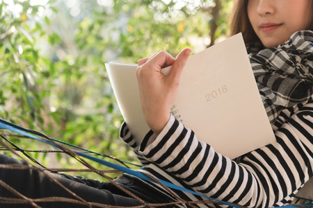 Beautiful young teenage woman write note for 2018 in white notebook