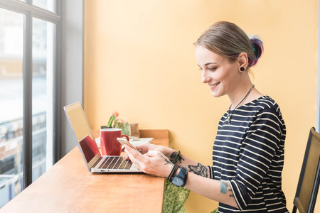 Russian woman working as freelance use smartphone and laptop in coffee shopの写真素材