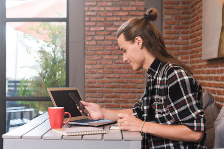 Male freelancer use smartphone and laptop in cafe, nomad worker conceptualの写真素材