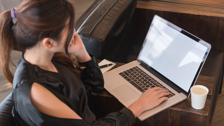 Beautiful asian woman in black dress working with laptop in coffeeshop, blank screen computer for mock up template or screen in sertionの写真素材