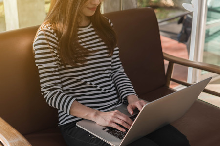 Beautiful young teenage woman freelance work with laptop at coffee shop in with sun light, freelance lifestyle conceptualの写真素材