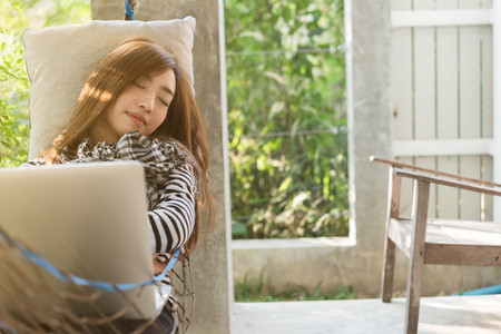 Young woman sleeping in hammock while use laptop, freelance life style conceptual, work anywhereの写真素材